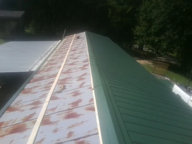 Old rusted panels beside newly installed green metal roofing — Wind Damage Roof Repair by Roofing Brothers in Isanti
