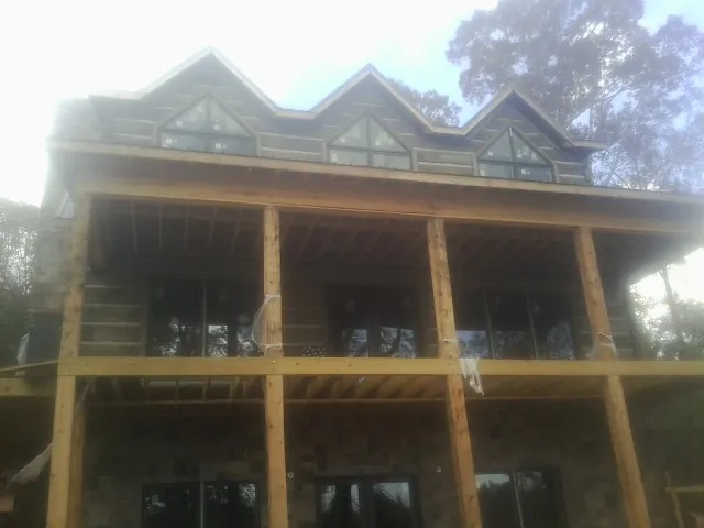 Dormers and porch framing on a large log home under construction — Roof Coating work by our crew in Isanti