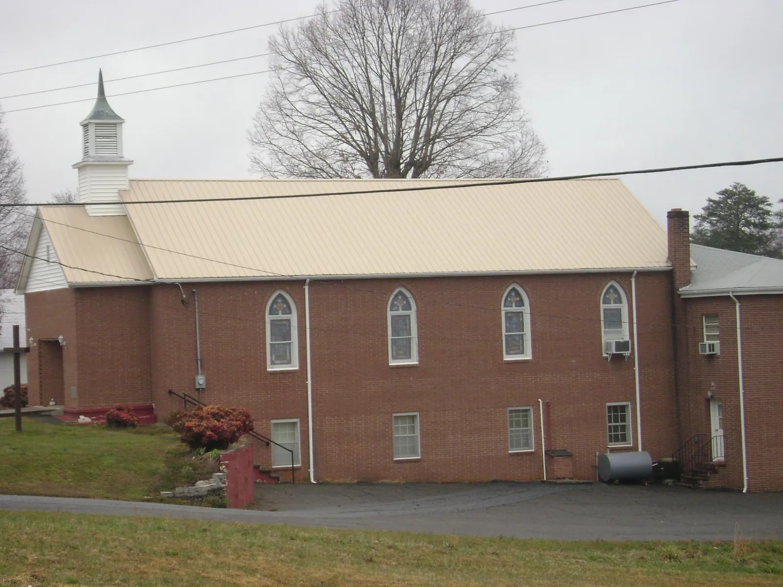 New tan metal roof on a brick church with a white steeple in Isanti