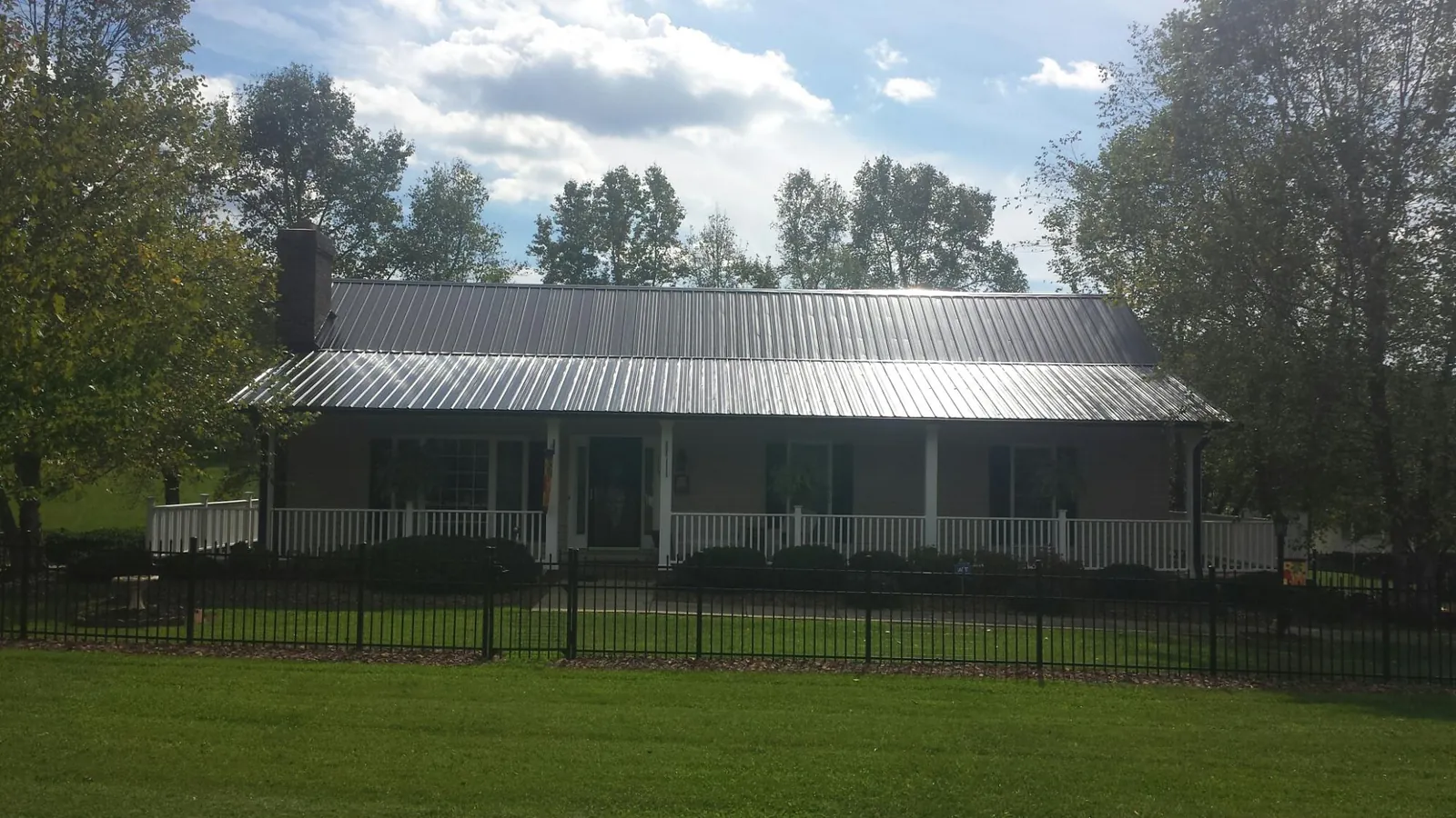 Gray metal roof on a brick ranch with a full width front porch — Gutter Guard Installation work by our crew in Isanti